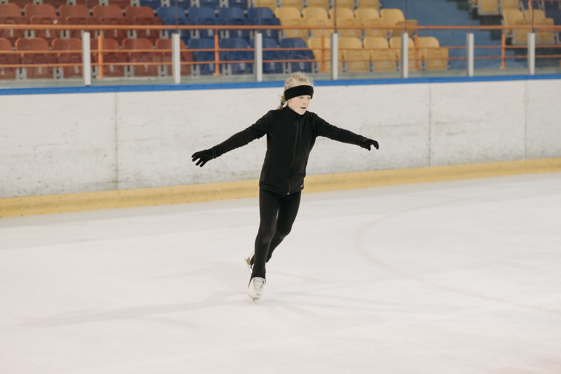 Girl in black attire figureskating at an indoor ice rink. Winter sports practice.