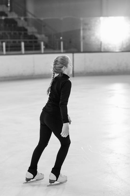 Grayscale Photo of Girl in Black Bodysuit doing Figure Skating