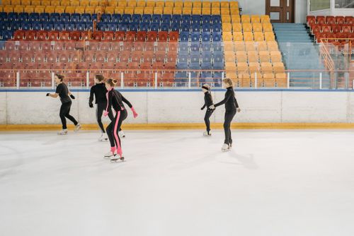 Free Five young skaters practice figure skating on an indoor ice rink, focusing on teamwork and technique. Stock Photo