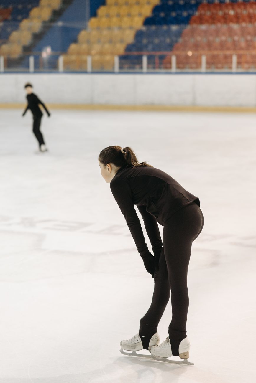 Twee jonge kunstschaatsers oefenen in een binnen ijsbaan en slaan een gracieuze pose aan.