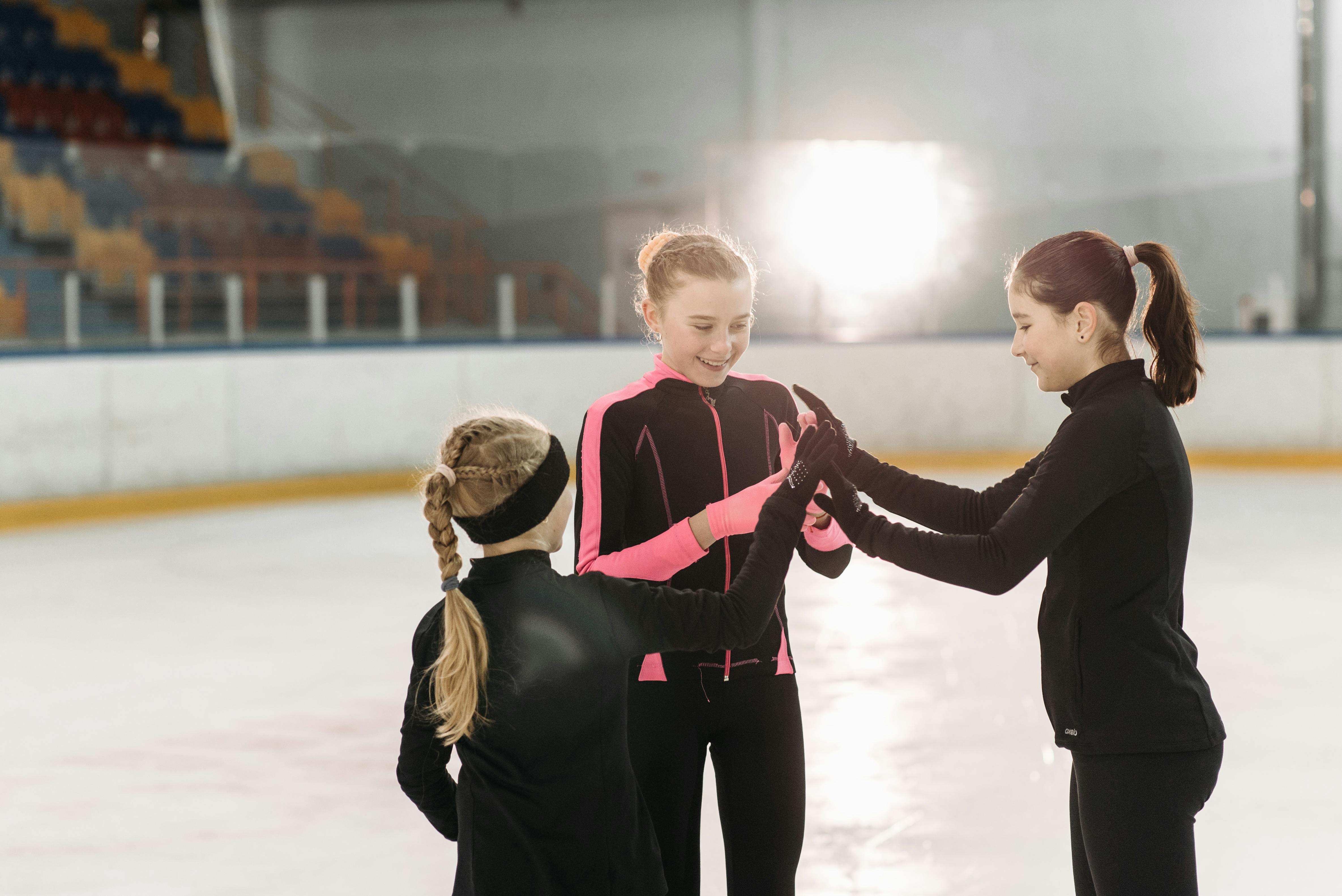girls in black bodysuit standing inside ice skating rink