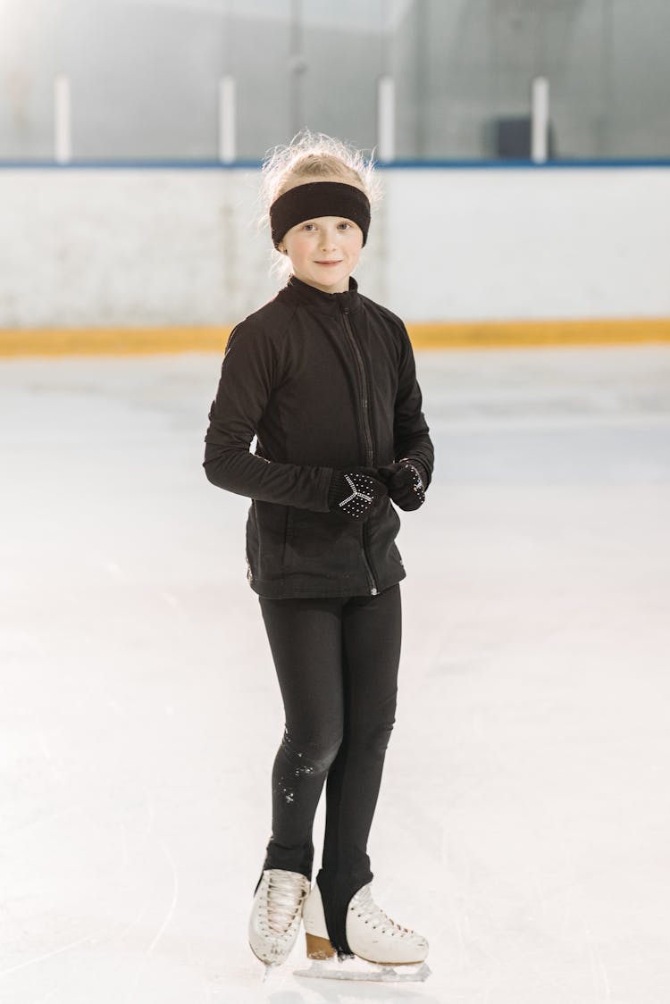 Young Girl Wearing Ice Skates Standing On Ice