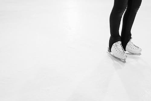 A Person in Black Leggings Wearing a Dirty Ice Skates