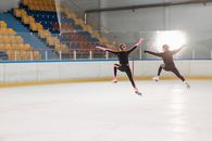 A Pair of Figure Skaters in Synchronized Jumping in the Air