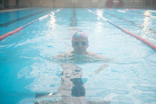 A woman swimmer practicing in an indoor pool with clear blue water.