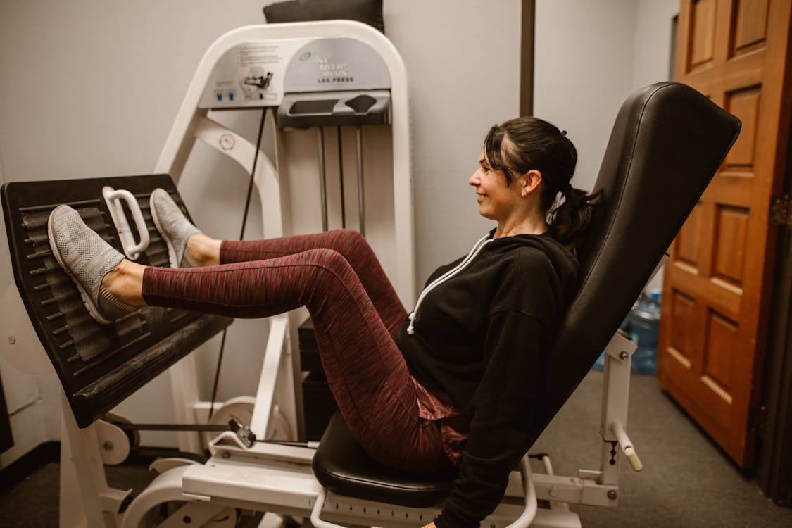 Free A woman works out on a leg press machine, promoting fitness and a healthy lifestyle Stock Photo