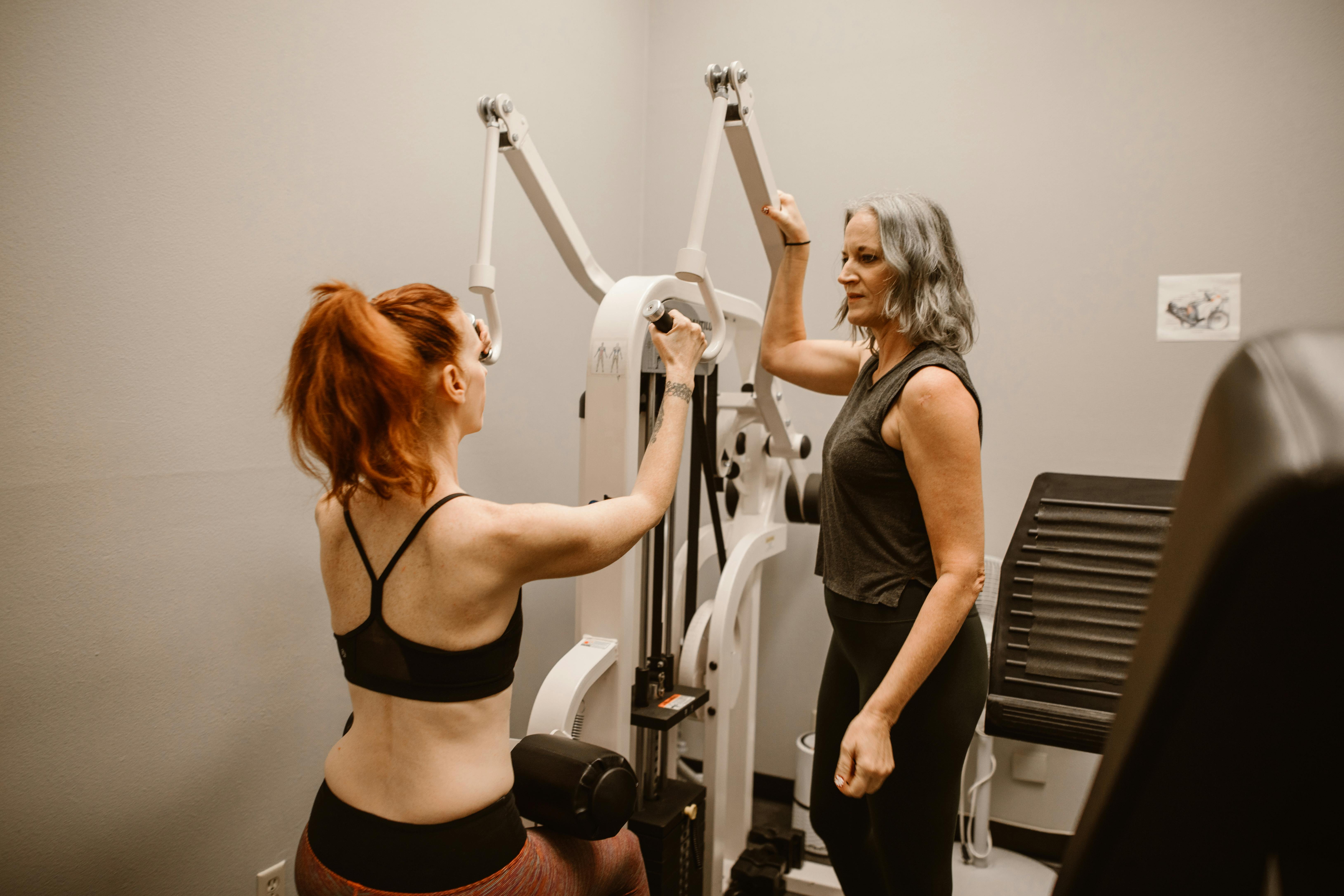 Two women engaged in a workout session using gym equipment, promoting fitness and empowerment.