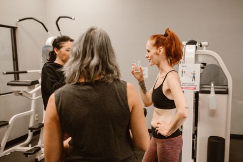 Free Three women chatting and hydrating in a gym environment, focusing on wellness and fitness. Stock Photo