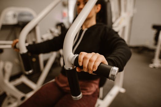 Close-up of a woman using a chest press machine in the gym for strength training.