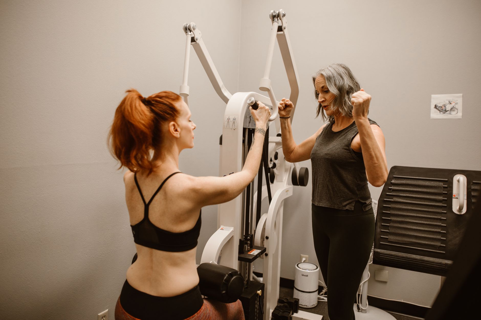 Two women working out with gym equipment indoors, focusing on fitness and healthy living.