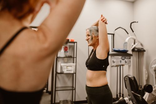 Free A middle-aged woman confidently stretches in a gym, embracing wellness and healthy living. Stock Photo
