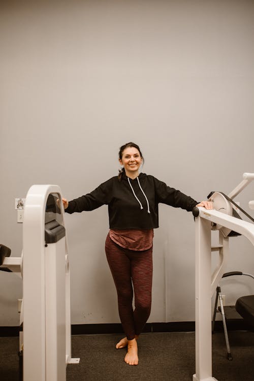 A Happy Woman Standing beside Gym Equipment