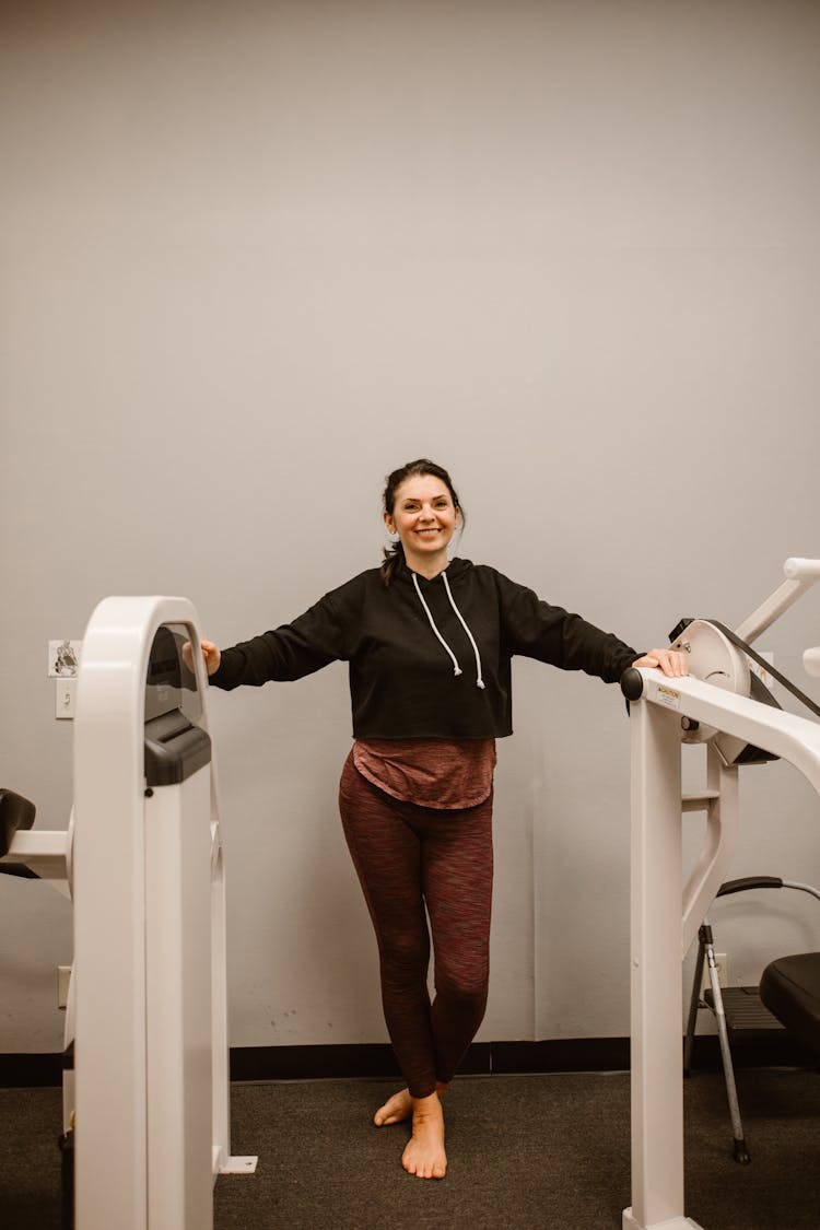 A Happy Woman Standing Beside Gym Equipment