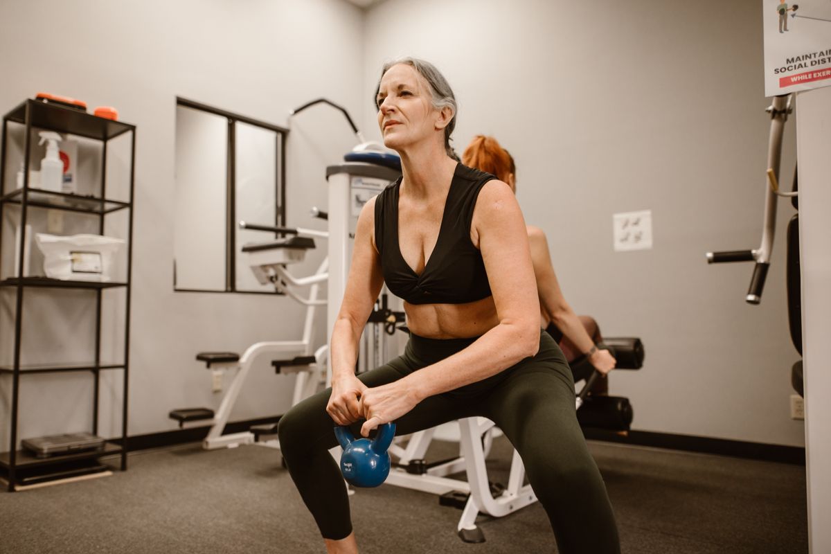Mulher madura treinando força com kettlebell na academia