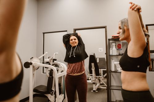 Free Women performing stretching exercises in a gym setting, promoting fitness and wellness. Stock Photo