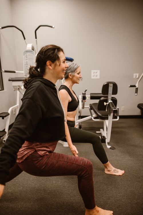 Free Two women stretching in a modern gym promoting wellness and fitness. Stock Photo