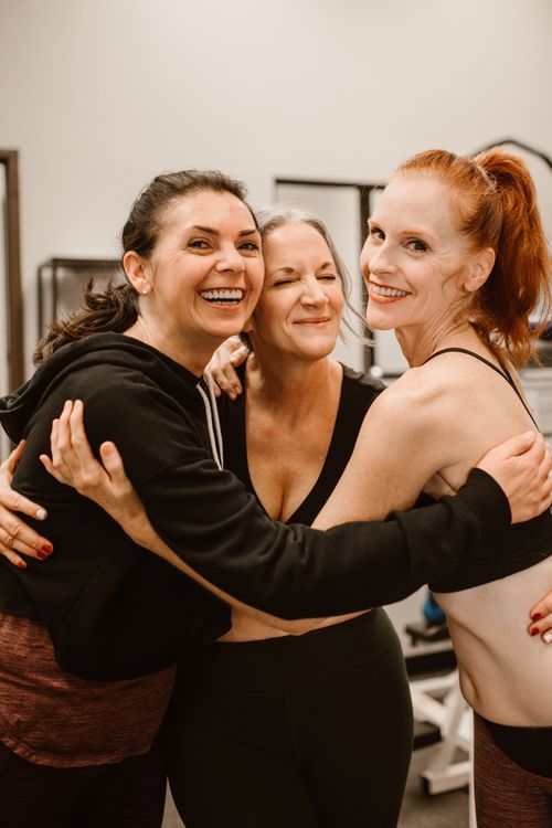 Free Three happy women hugging at the gym, celebrating friendship and wellness. Stock Photo