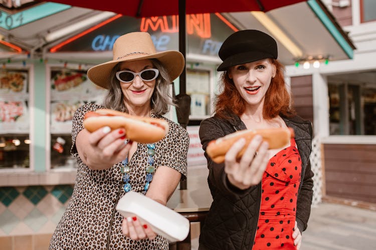 Two Women Holding Hotdogs