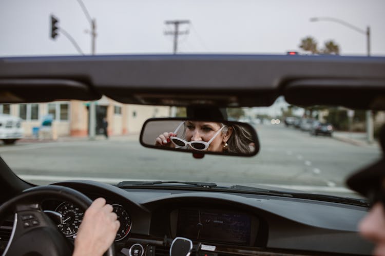 Reflection Of An Elderly Woman On Rear View Mirror Driving A Car