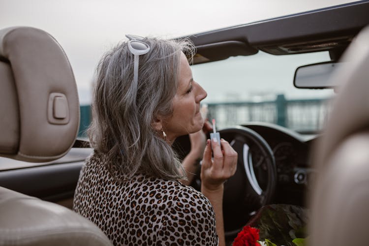 Stylish Woman Applying Lip Gloss While Driving Car