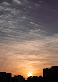Captivating sunset with silhouetted buildings and dramatic clouds in the sky.