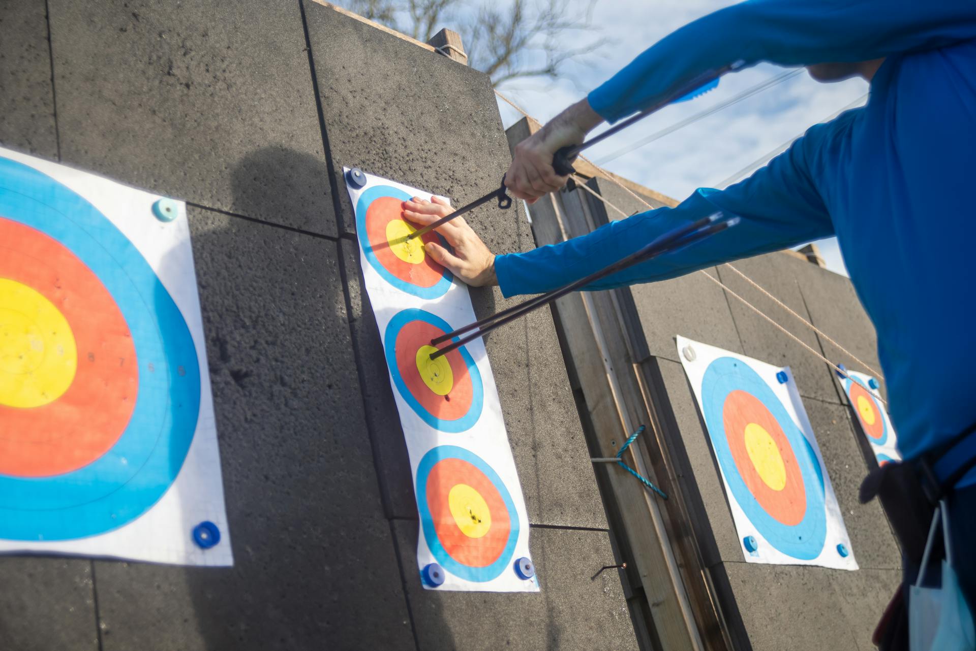 Person pulling Arrows from Archery Target