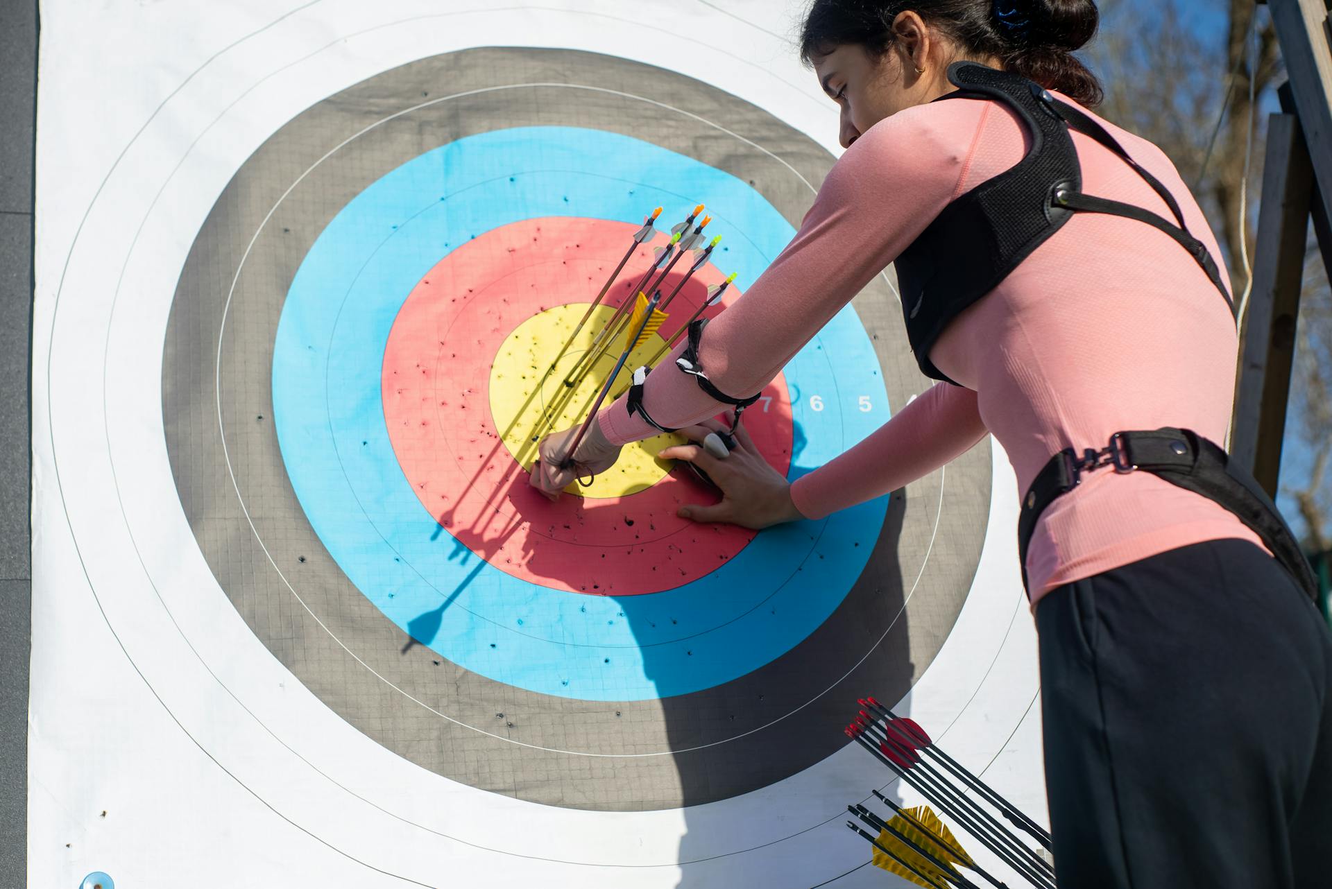 Woman Pulling Arrows from Archery Target Board