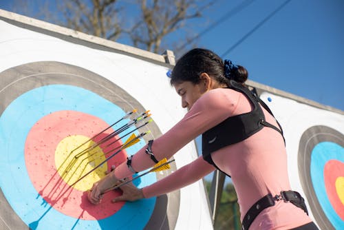 Free Woman Pulling Arrows from Archery Target Board Stock Photo