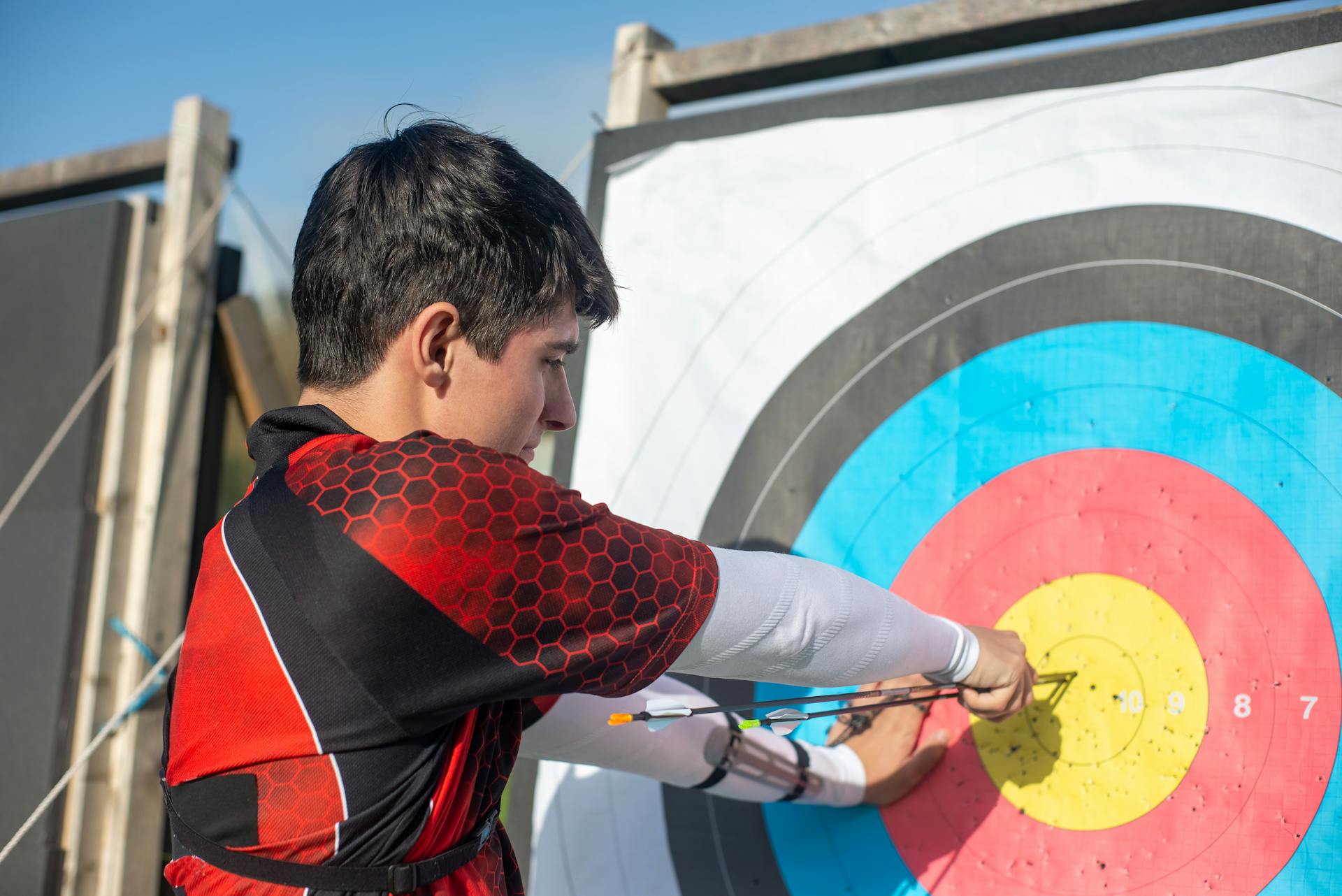 Man Pulling Arrows from Archery Target Board