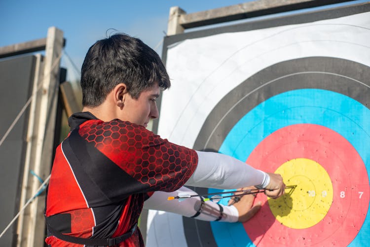 Man Pulling Arrows From Archery Target Board