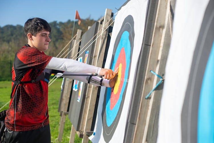 Archer Pulling An Arrow From An Archery Target Board 