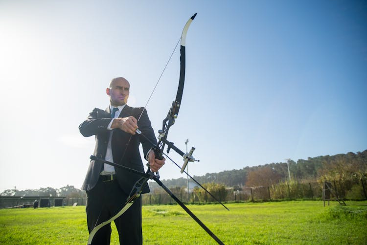 Man In Formal Wear Holding Compound Bow And Arrow