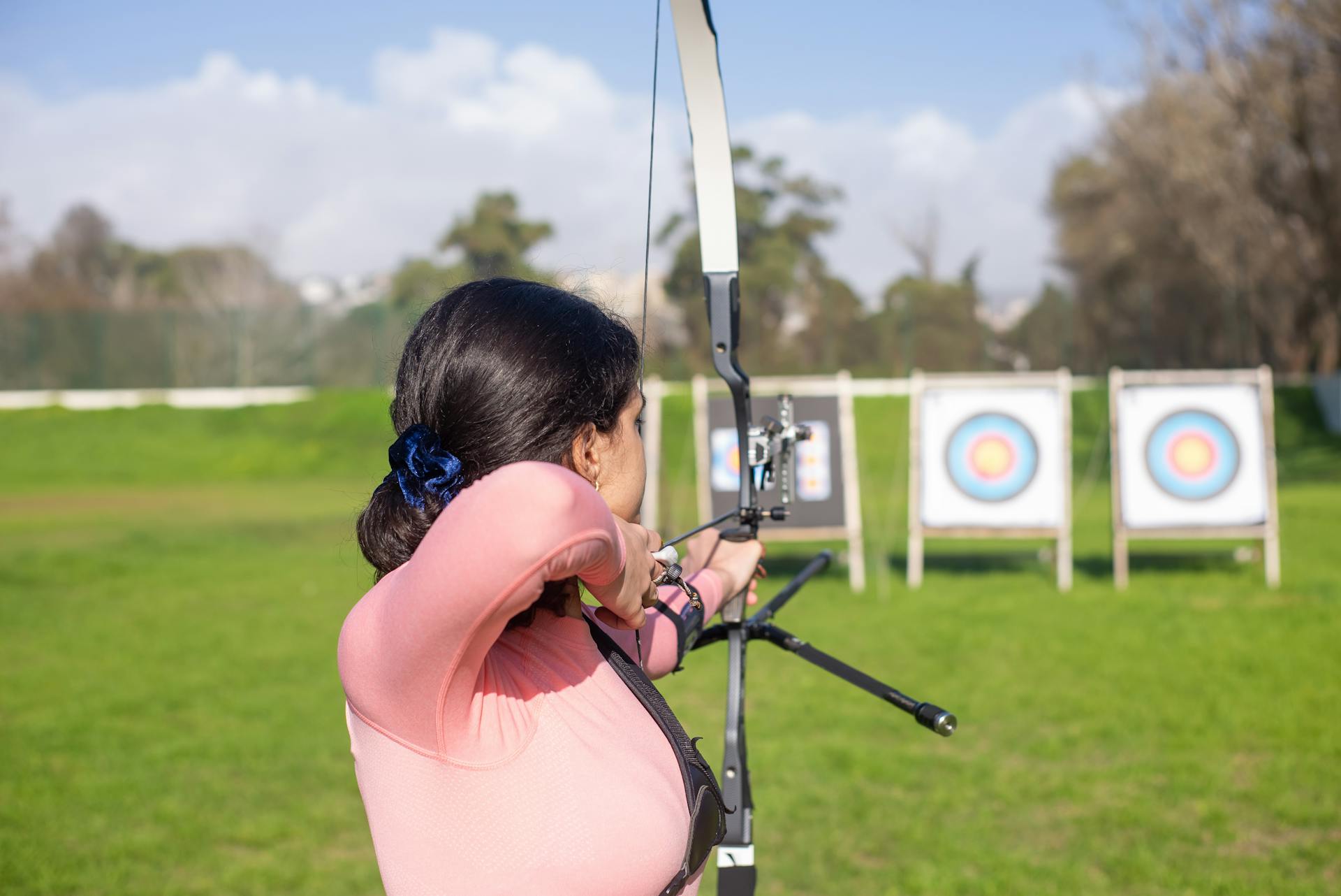 Woman Aiming Bow and Arrow on Archery Target Board