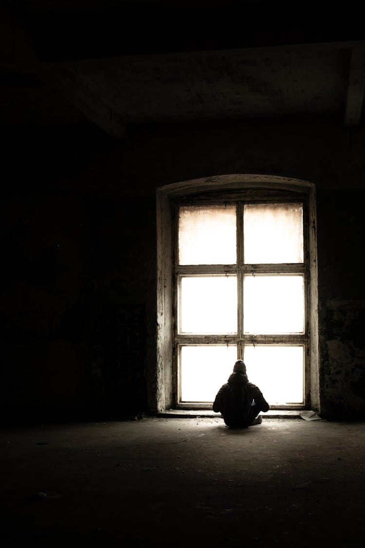 A Person Looking Out The Window From An Abandoned Building