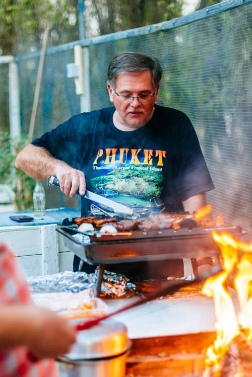 Free An elderly man grills food outdoors in South Africa, surrounded by flames and enjoying the summer day. Stock Photo