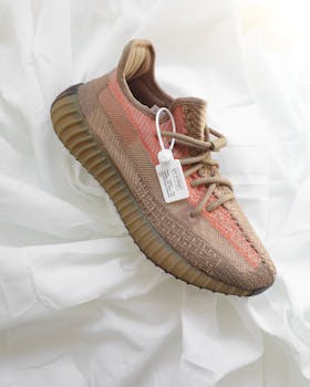 High-quality photo of a stylish brown sneaker with a tag on white fabric background.