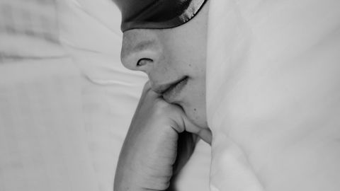 Black and white image of a woman sleeping peacefully with a sleep mask on.