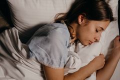 A serene young woman peacefully sleeping on a white pillow indoors at night.