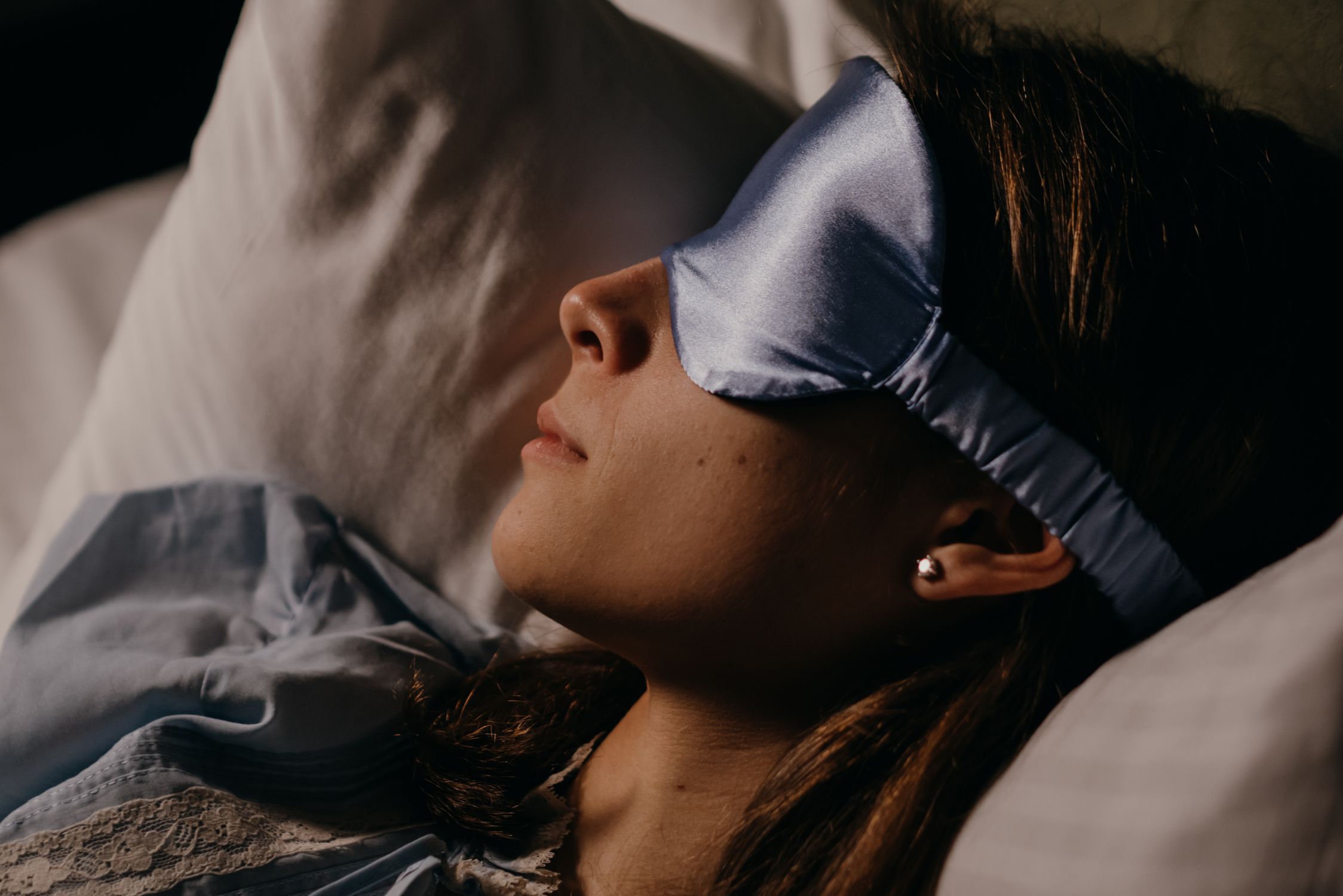 Close-up of a woman wearing a sleep mask resting in bed