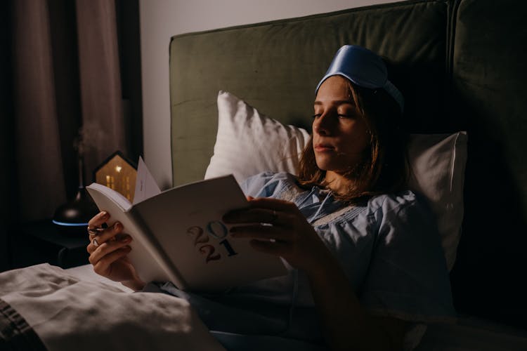 A Woman Using Her Journal While In Bed