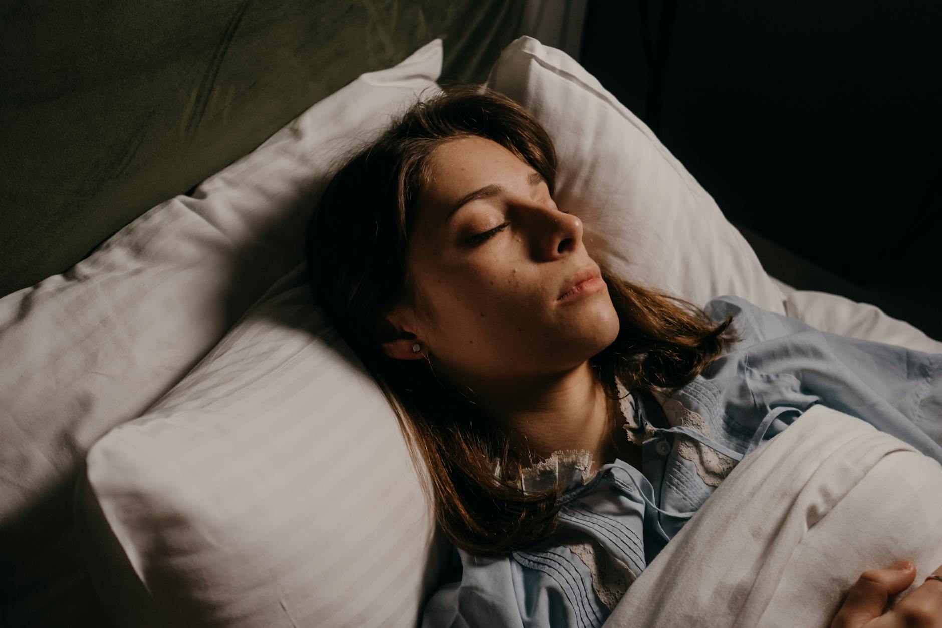 Woman sleeping peacefully in bed, highlighting comfort and serenity in a cozy bedroom setting.