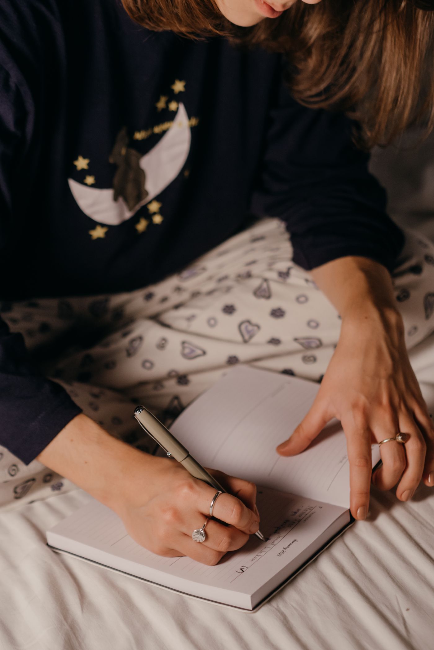 A woman in sleepwear writing in a notebook