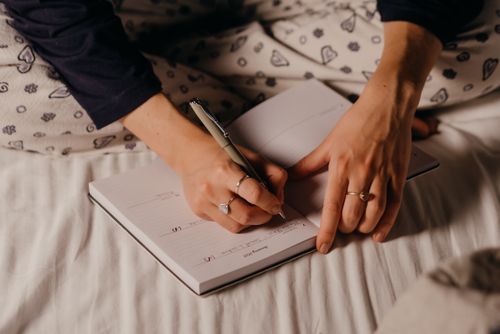 Free Close-up of a person's hands writing in a journal, showcasing a cozy nighttime ambiance. Stock Photo