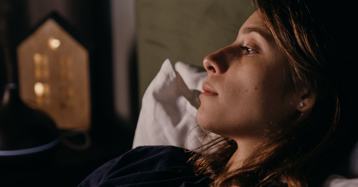 Close-up de uma mulher descansando em ambientes internos à noite, mostrando uma atmosfera serena e relaxada.