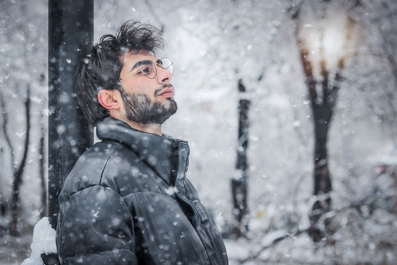 Man in a black puffer jacket in falling snow