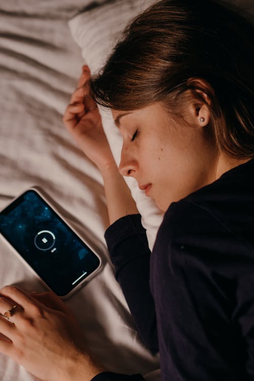 Free Woman Lying Beside a Smartphone Stock Photo