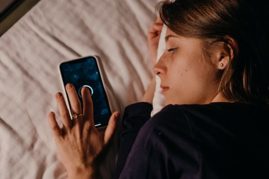 A woman lying in bed, engaged with her smartphone, creating a tranquil nighttime scene.