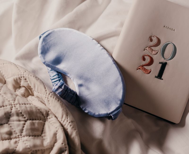 A close-up of a sleep time patch applied on a wrist in a calm bedroom setting.