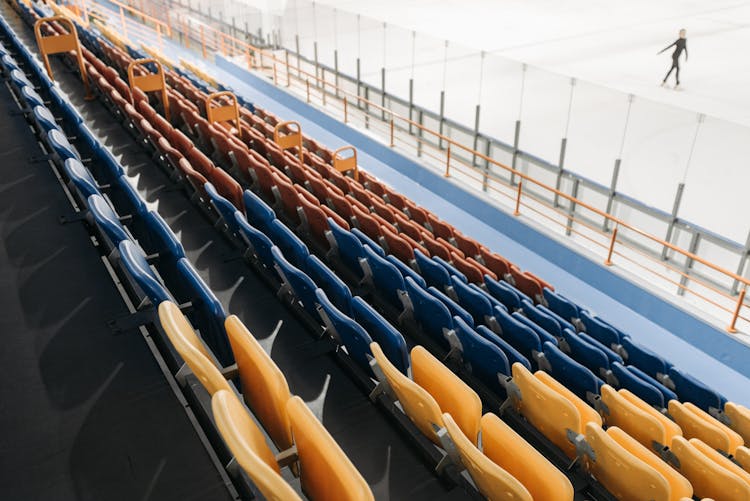 A Person Ice Skating On A Stadium With Empty Bleachers