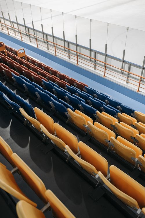 Free Colorful empty bleachers overlooking an indoor ice skating rink, capturing a peaceful stadium scene. Stock Photo